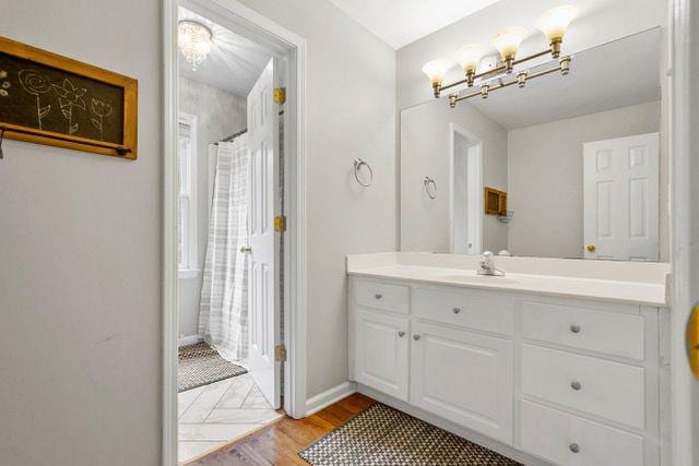 full bathroom with baseboards, wood finished floors, and vanity