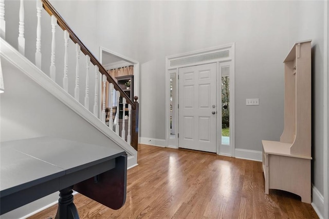 entryway with wood finished floors, a towering ceiling, baseboards, and stairs