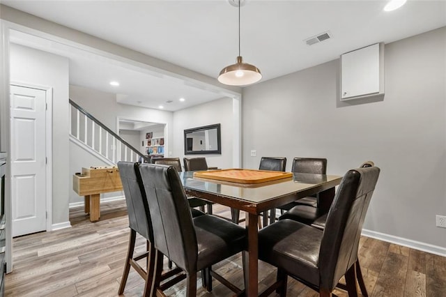 dining space with baseboards, visible vents, light wood finished floors, and stairs