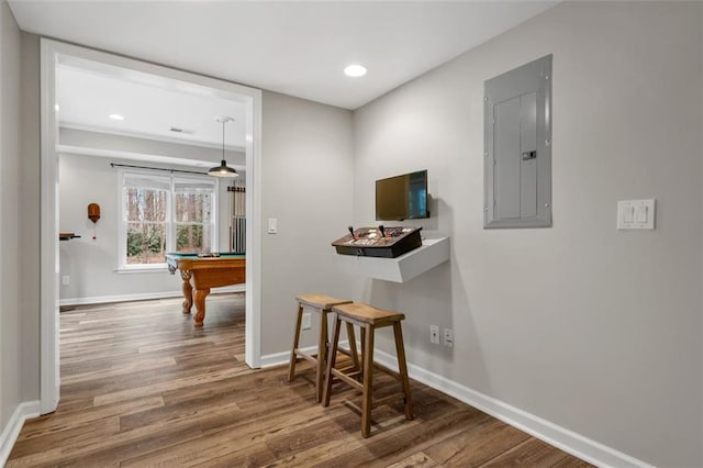 hallway featuring electric panel, visible vents, baseboards, and wood finished floors