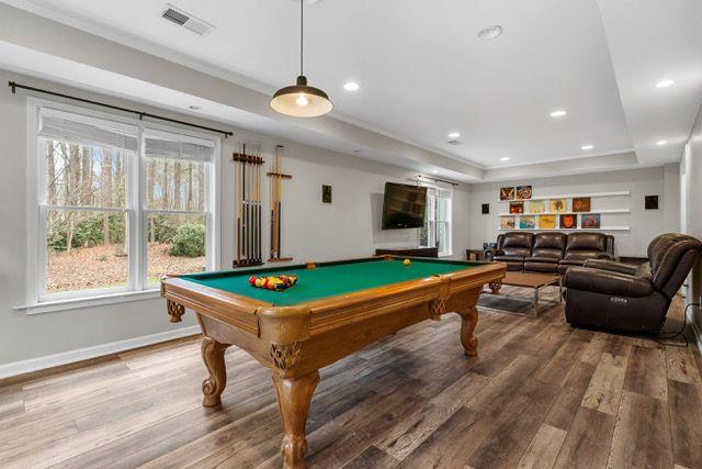 rec room featuring a tray ceiling, recessed lighting, visible vents, wood finished floors, and baseboards