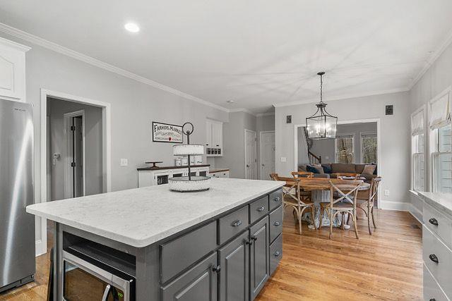 kitchen with a center island, white cabinets, light hardwood / wood-style flooring, a notable chandelier, and stainless steel appliances