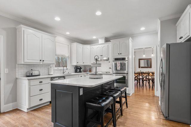 dining area featuring light hardwood / wood-style floors, ornamental molding, and ornate columns