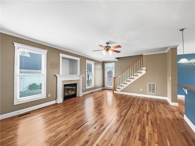 unfurnished living room with visible vents, crown molding, and stairs