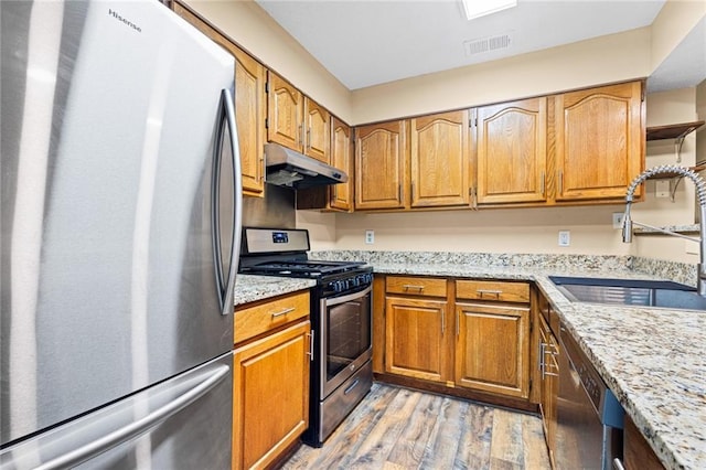 98 Hampshire Ct, Avondale Estates, GA 30002 - kitchen featuring stainless steel appliances, under cabinet range hood, a sink, light wood finished floors, and brown cabinets