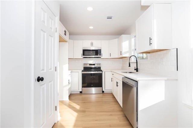 kitchen with stainless steel appliances, backsplash, white cabinetry, and sink