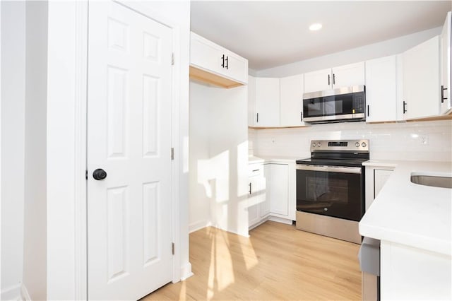 kitchen featuring white cabinetry, appliances with stainless steel finishes, tasteful backsplash, and light wood-type flooring