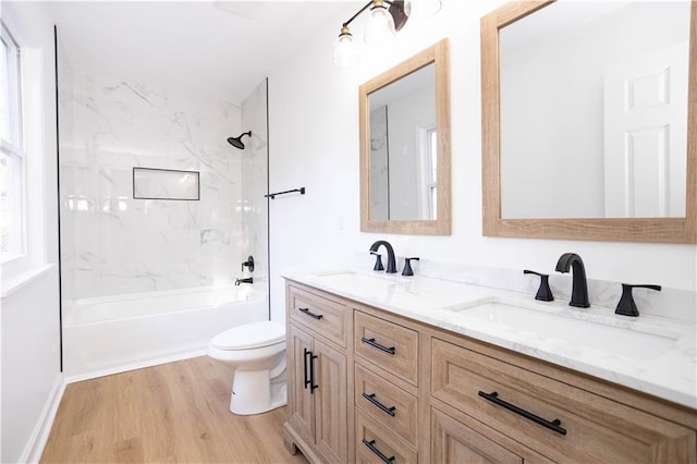 full bathroom featuring toilet, tiled shower / bath, wood-type flooring, and vanity