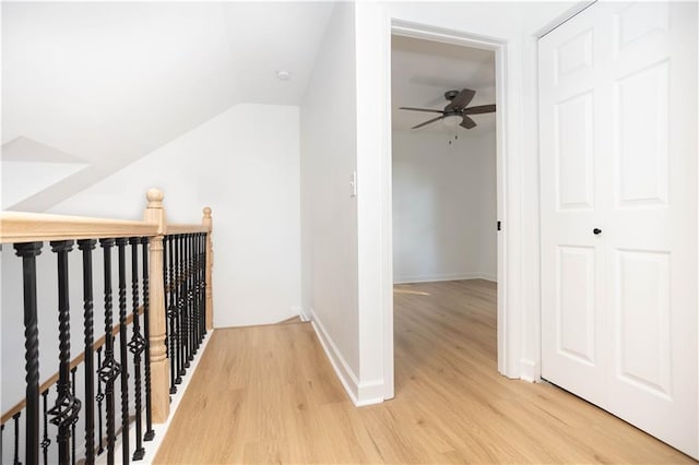 hallway with vaulted ceiling and light wood-type flooring