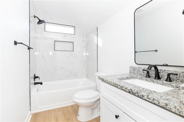 full bathroom with toilet, tiled shower / bath, hardwood / wood-style floors, and vanity