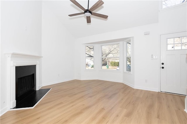 unfurnished living room with light wood-type flooring, ceiling fan, and high vaulted ceiling