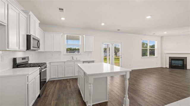 kitchen featuring sink, dark wood-type flooring, appliances with stainless steel finishes, white cabinetry, and a kitchen island