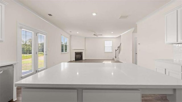 kitchen featuring a spacious island, crown molding, dishwasher, ceiling fan, and white cabinets