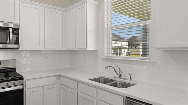 kitchen with stainless steel appliances, white cabinetry, sink, and tasteful backsplash