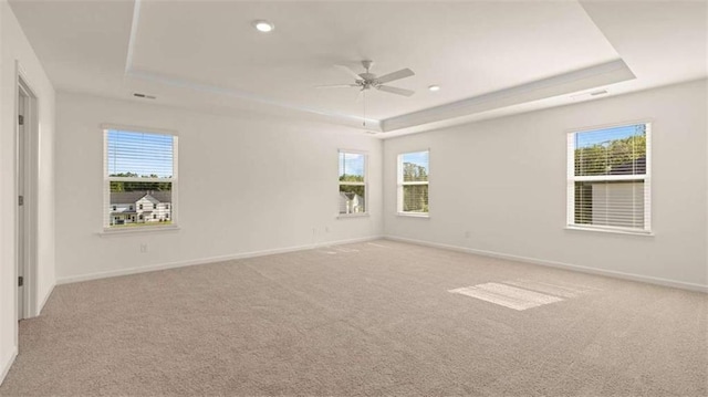 carpeted empty room with ceiling fan and a raised ceiling