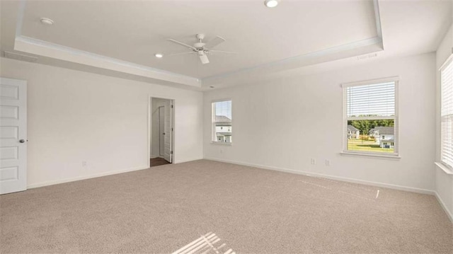 carpeted spare room featuring a raised ceiling and ceiling fan