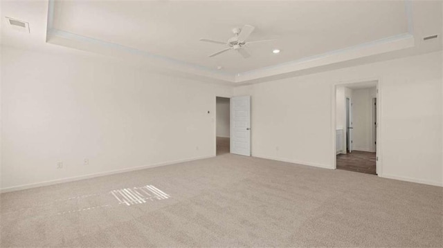 carpeted spare room featuring a raised ceiling and ceiling fan