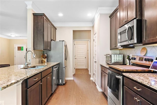 110 Collingwood Lndg, Covington, GA 30016 - kitchen with stainless steel appliances, light wood-style floors, ornamental molding, dark brown cabinets, and light stone countertops