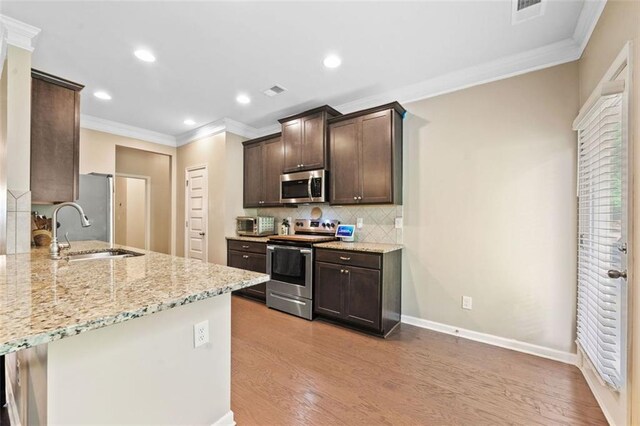 110 Collingwood Lndg, Covington, GA 30016 - kitchen featuring stainless steel appliances, dark brown cabinetry, crown molding, light wood-type flooring, and light stone countertops