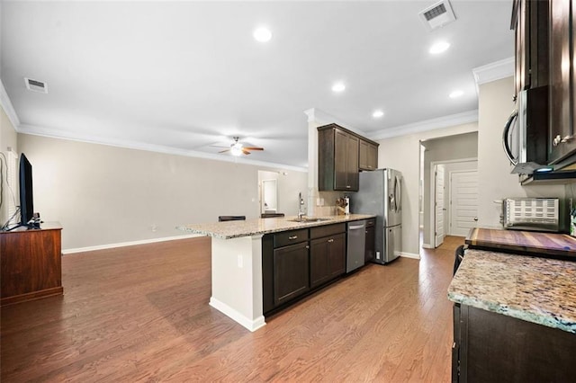 110 Collingwood Lndg, Covington, GA 30016 - kitchen featuring appliances with stainless steel finishes, crown molding, ceiling fan, dark brown cabinetry, and light wood finished floors