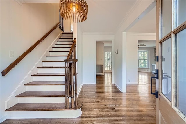 stairway with wood-type flooring and crown molding