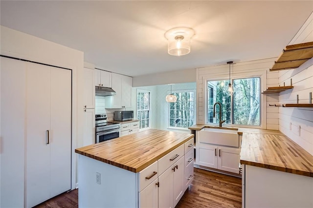 kitchen with sink, wooden counters, pendant lighting, stainless steel range with electric stovetop, and white cabinets