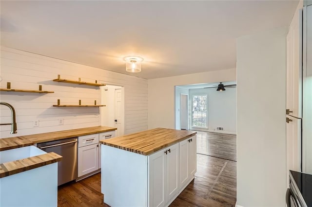 kitchen featuring wood counters, stainless steel dishwasher, sink, white cabinetry, and a kitchen island