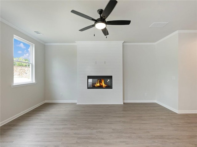 unfurnished living room with light hardwood / wood-style floors, ornamental molding, a large fireplace, and ceiling fan