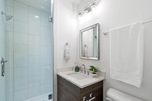 bathroom with vanity, a shower with shower door, and toilet