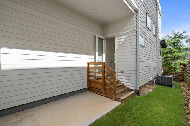 view of exterior entry featuring a yard and central air condition unit