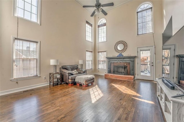 living room featuring a healthy amount of sunlight, a fireplace, baseboards, and wood finished floors