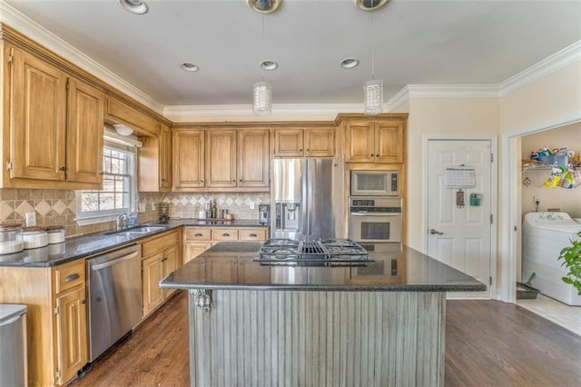 kitchen with stainless steel appliances, a sink, ornamental molding, dark wood finished floors, and washer / dryer