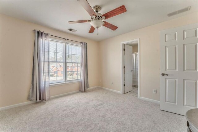 carpeted spare room featuring ceiling fan, visible vents, and baseboards