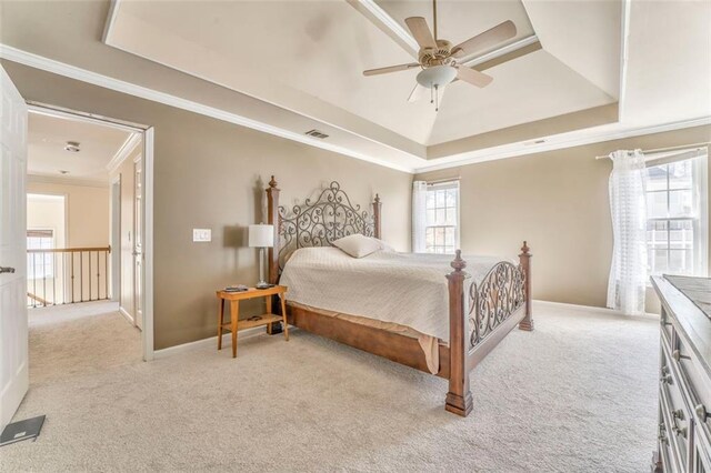 carpeted bedroom with a ceiling fan, visible vents, baseboards, ornamental molding, and a tray ceiling