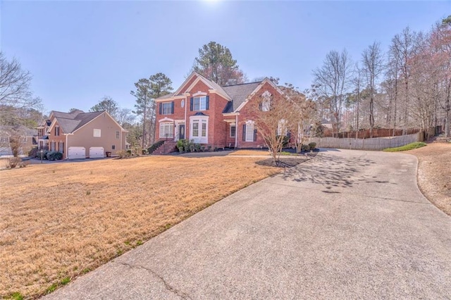 view of front of home with a garage, brick siding, a front yard, and fence