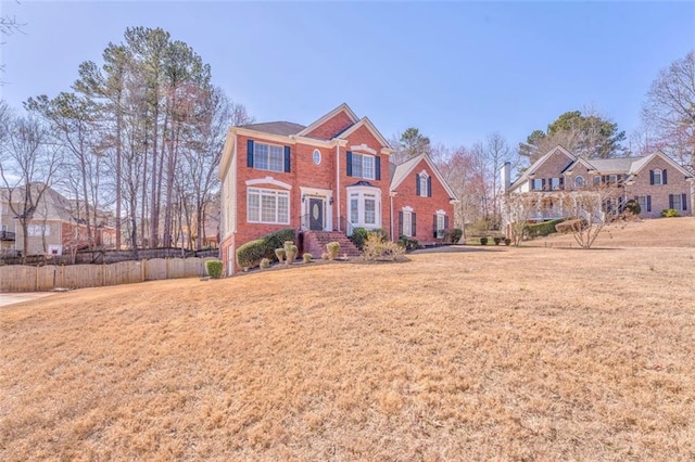 view of front of home featuring a front lawn, fence, and brick siding