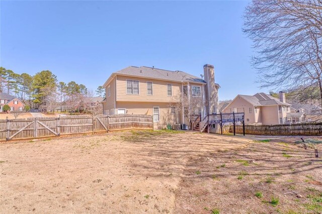 rear view of house with a chimney, stairway, a gate, a fenced backyard, and a wooden deck