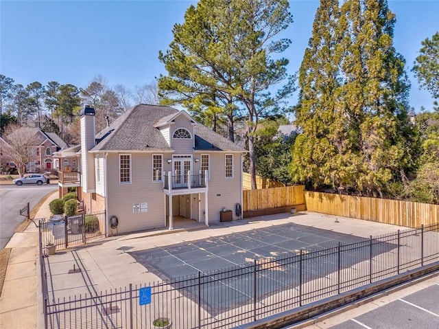 exterior space with a chimney, a patio area, fence, and a balcony