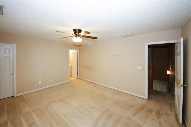 spare room with ceiling fan, light colored carpet, and a textured ceiling