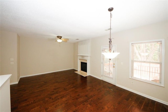 unfurnished living room featuring ceiling fan and dark wood-type flooring