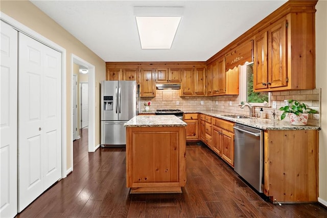 3012 Cypress Cv, Ball Ground, GA 30107 - kitchen featuring appliances with stainless steel finishes, tasteful backsplash, a sink, brown cabinets, and light stone countertops