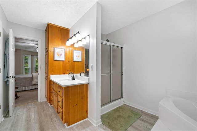3012 Cypress Cv, Ball Ground, GA 30107 - bathroom featuring wood finished floors, a stall shower, vanity, a bath, and a textured ceiling