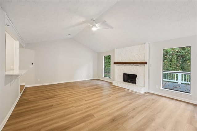 unfurnished living room featuring vaulted ceiling, a fireplace, and light hardwood / wood-style floors