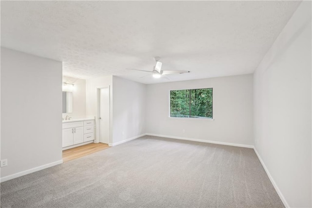 empty room with light carpet, sink, and ceiling fan