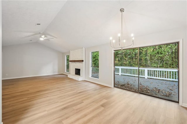 unfurnished living room featuring a wealth of natural light, lofted ceiling, ceiling fan with notable chandelier, and light hardwood / wood-style floors