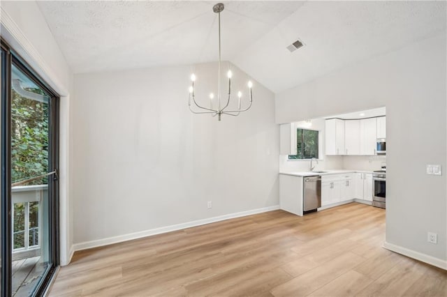 unfurnished dining area with sink, a textured ceiling, light hardwood / wood-style flooring, and an inviting chandelier