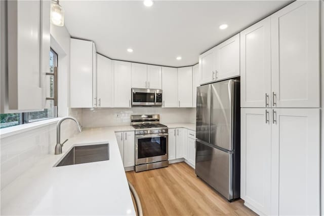 kitchen featuring hanging light fixtures, appliances with stainless steel finishes, sink, and white cabinets