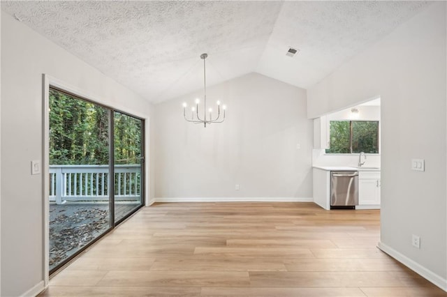 unfurnished dining area featuring light hardwood / wood-style floors, lofted ceiling, plenty of natural light, and a chandelier