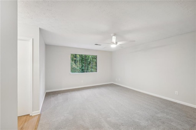 empty room with a textured ceiling, light colored carpet, and ceiling fan