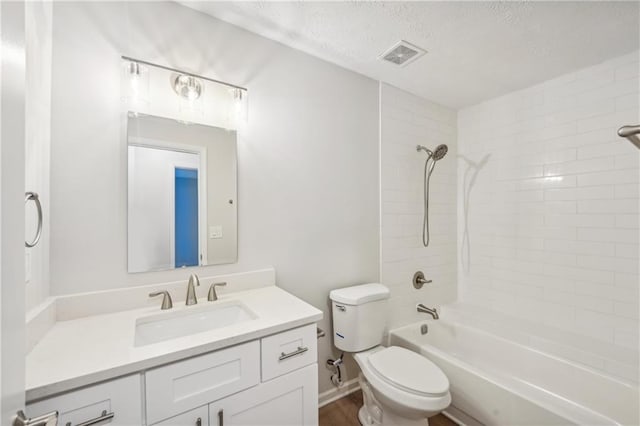 full bathroom with toilet, wood-type flooring, tiled shower / bath, vanity, and a textured ceiling